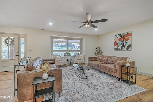 living room with ceiling fan, plenty of natural light, a textured ceiling, and light wood-type flooring