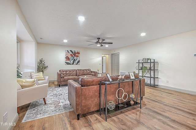 living room featuring ceiling fan, a textured ceiling, and light hardwood / wood-style flooring