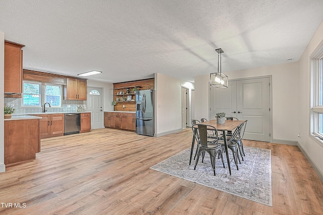 dining space with light hardwood / wood-style floors, sink, and a textured ceiling