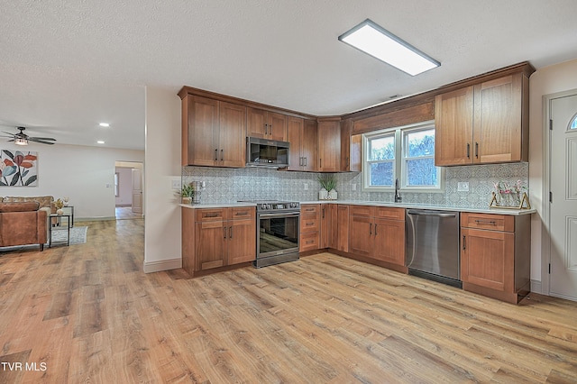 kitchen with light hardwood / wood-style floors, sink, appliances with stainless steel finishes, and ceiling fan