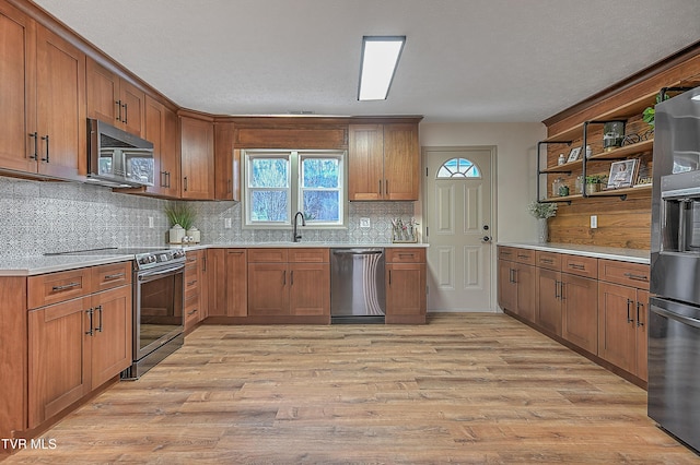 kitchen with a textured ceiling, appliances with stainless steel finishes, light hardwood / wood-style flooring, and sink