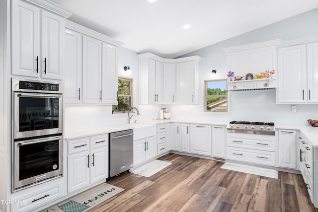 kitchen featuring sink, appliances with stainless steel finishes, vaulted ceiling, and white cabinetry