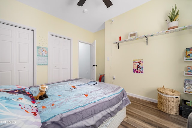 bedroom featuring hardwood / wood-style flooring, ceiling fan, and multiple closets