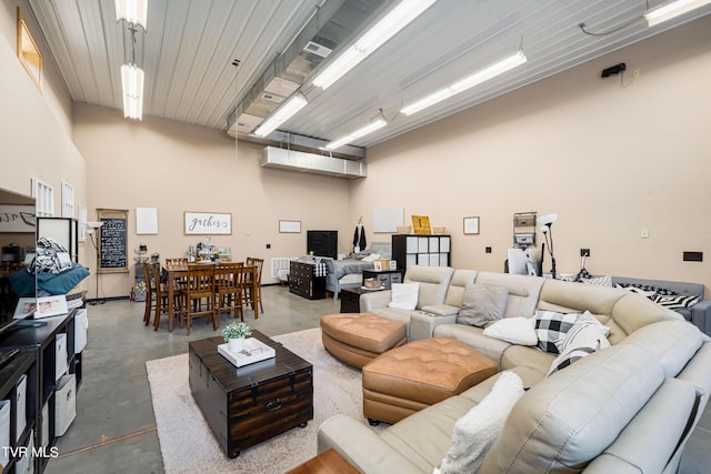 living room featuring a towering ceiling and concrete floors