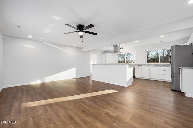 interior space featuring a kitchen island, white cabinetry, island range hood, stainless steel refrigerator, and ceiling fan