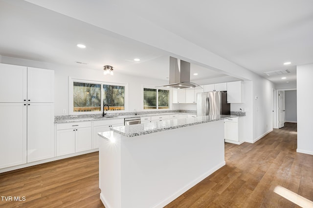 kitchen featuring white cabinetry, island exhaust hood, stainless steel appliances, and a kitchen island