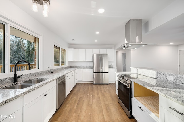 kitchen featuring white cabinetry, island exhaust hood, appliances with stainless steel finishes, light stone countertops, and sink