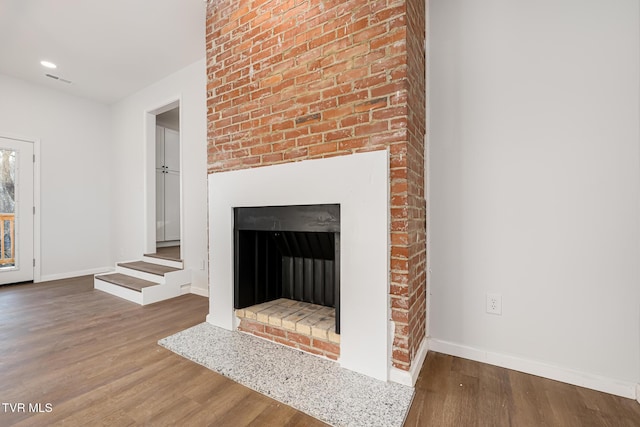 room details featuring a brick fireplace and wood-type flooring