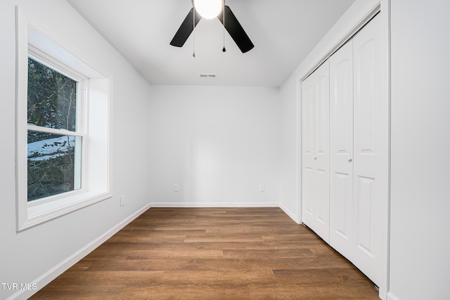 unfurnished bedroom with ceiling fan, dark wood-type flooring, and a closet