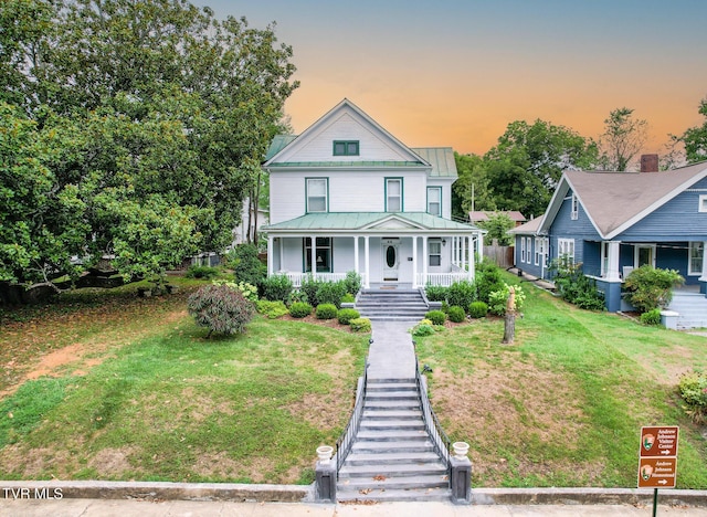 view of front of property with covered porch and a lawn