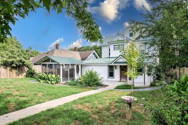 back of property featuring a lawn and a sunroom