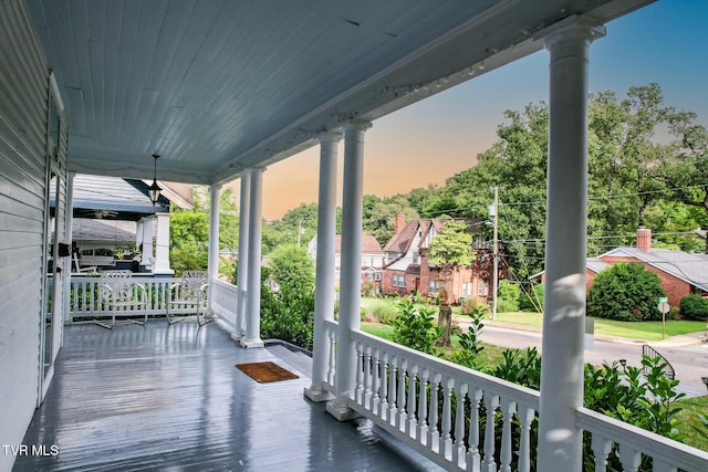 deck at dusk featuring covered porch