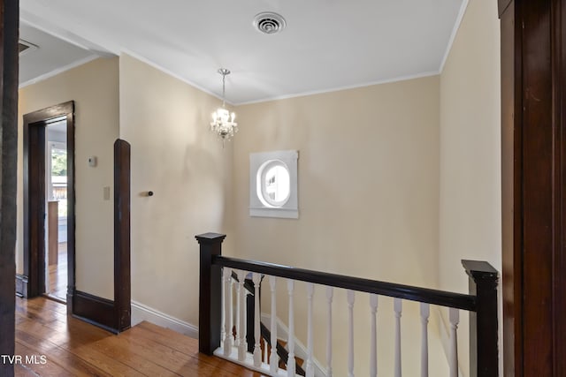 hall with hardwood / wood-style flooring, an inviting chandelier, and crown molding