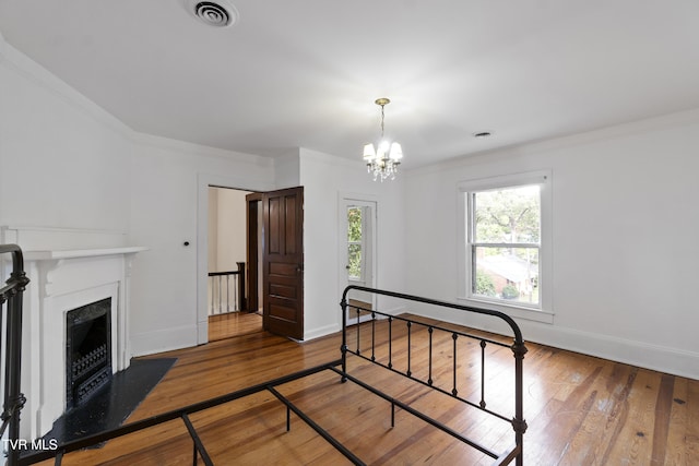 bedroom featuring an inviting chandelier, hardwood / wood-style floors, and crown molding