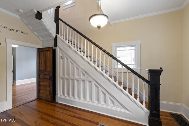 stairs with ornamental molding and hardwood / wood-style floors