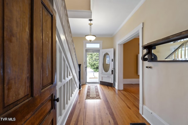 foyer featuring ornamental molding and light hardwood / wood-style flooring