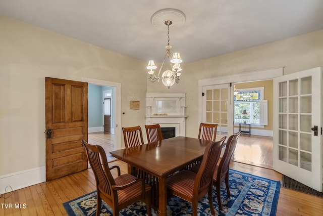 dining room featuring french doors, a notable chandelier, and light hardwood / wood-style flooring