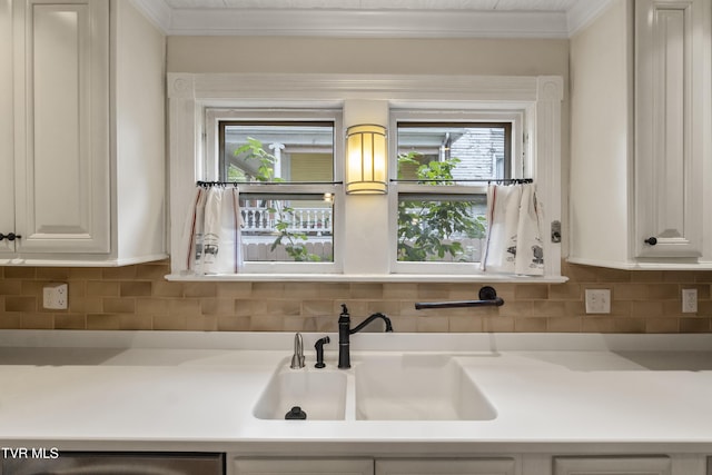 kitchen featuring sink, white cabinets, backsplash, and crown molding