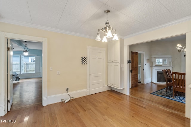 dining area with light hardwood / wood-style floors, an inviting chandelier, and crown molding