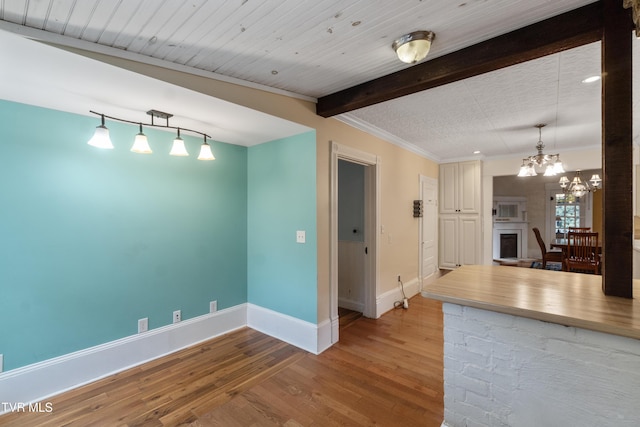 empty room with light hardwood / wood-style floors, a notable chandelier, and beam ceiling