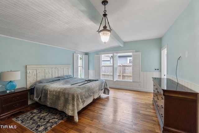 bedroom featuring vaulted ceiling with beams and hardwood / wood-style flooring