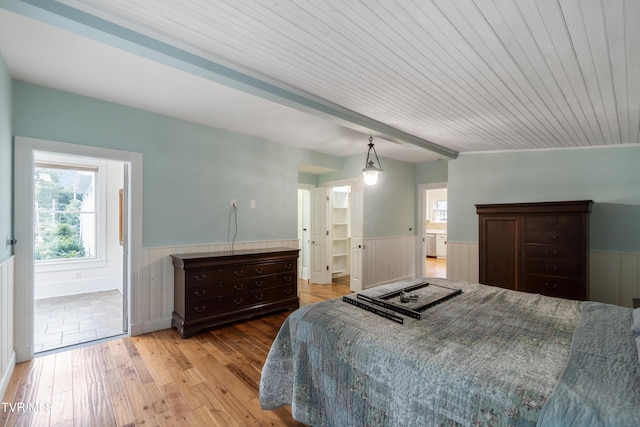 bedroom featuring ensuite bathroom, wooden ceiling, light hardwood / wood-style floors, and beamed ceiling