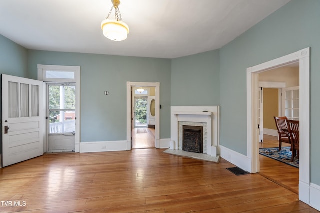 unfurnished living room featuring light hardwood / wood-style floors and a brick fireplace