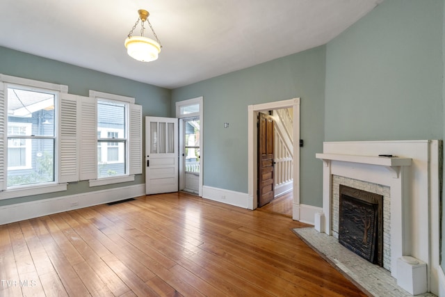 unfurnished living room featuring hardwood / wood-style flooring and a stone fireplace