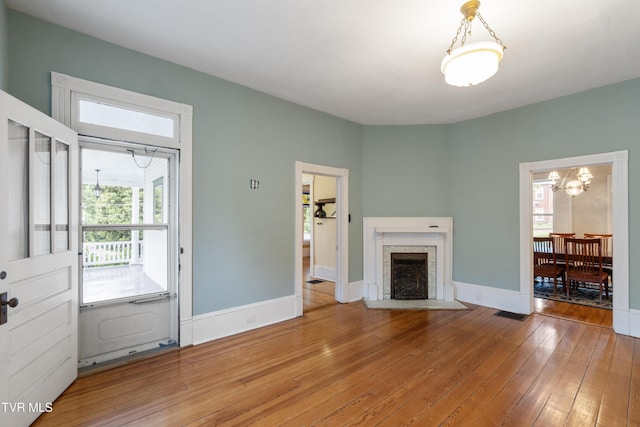 unfurnished living room featuring a fireplace, hardwood / wood-style flooring, and a chandelier