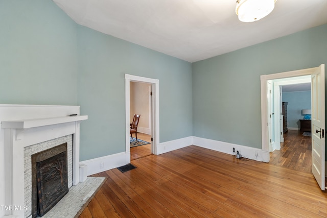 unfurnished living room with a brick fireplace and light wood-type flooring