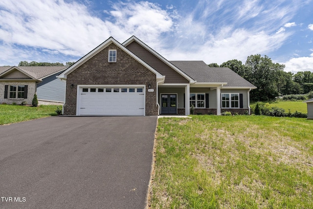 craftsman house featuring aphalt driveway, an attached garage, brick siding, and a front yard