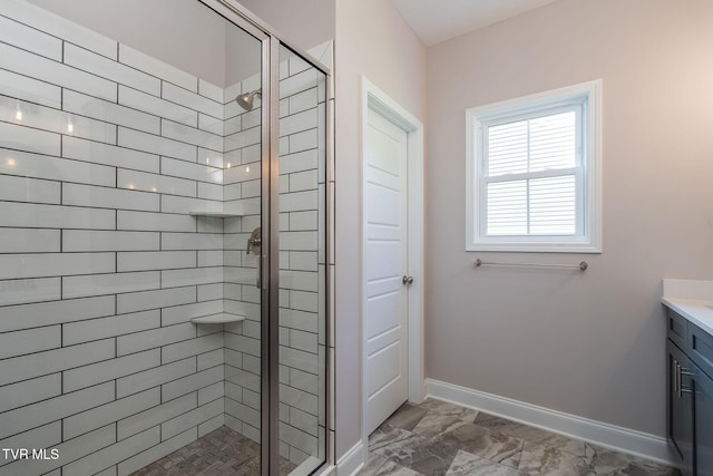 full bath featuring marble finish floor, a stall shower, vanity, and baseboards