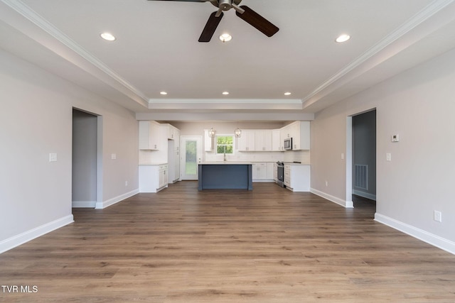 unfurnished living room featuring crown molding, recessed lighting, wood finished floors, and baseboards