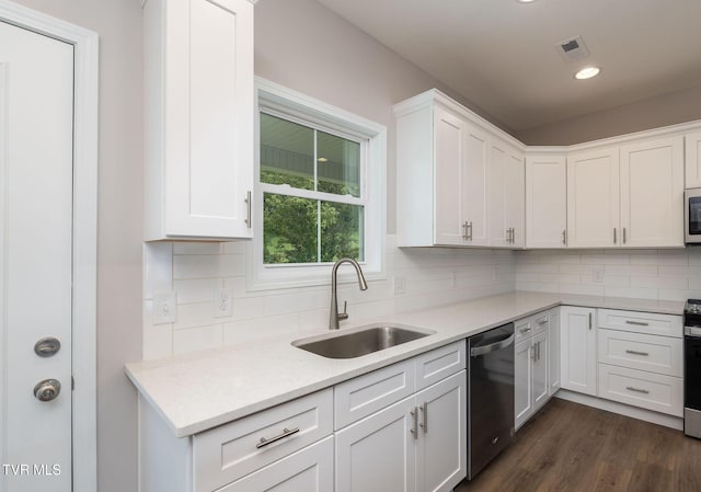 kitchen with a sink, appliances with stainless steel finishes, dark wood finished floors, and white cabinetry