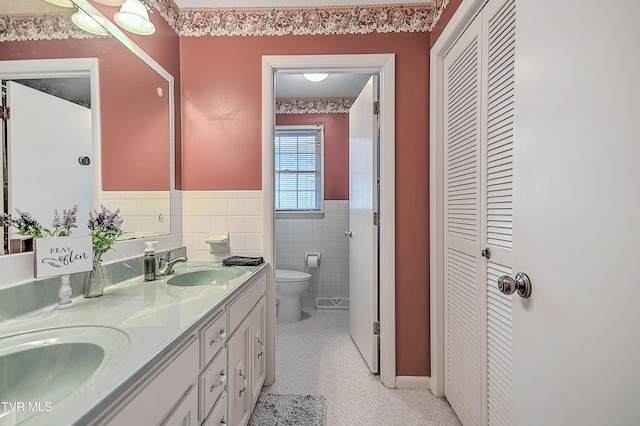 bathroom with tile walls, toilet, vanity, and a textured ceiling