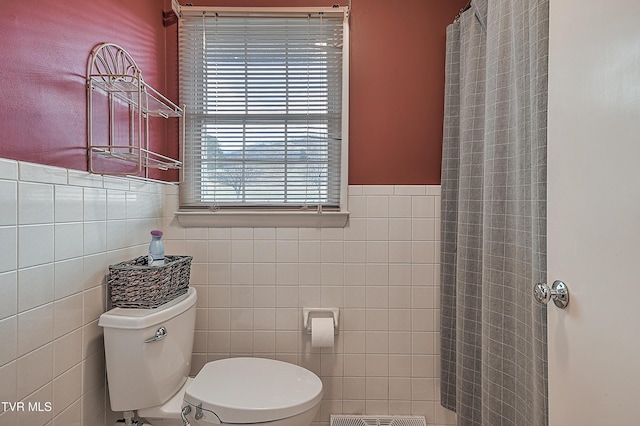 bathroom featuring toilet and tile walls