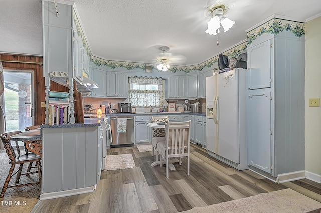 kitchen featuring stainless steel dishwasher, white fridge with ice dispenser, hardwood / wood-style floors, and a center island