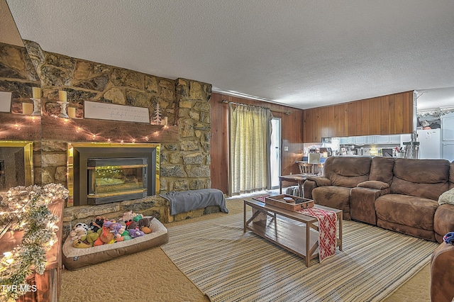 living room with a textured ceiling, wood walls, and a fireplace