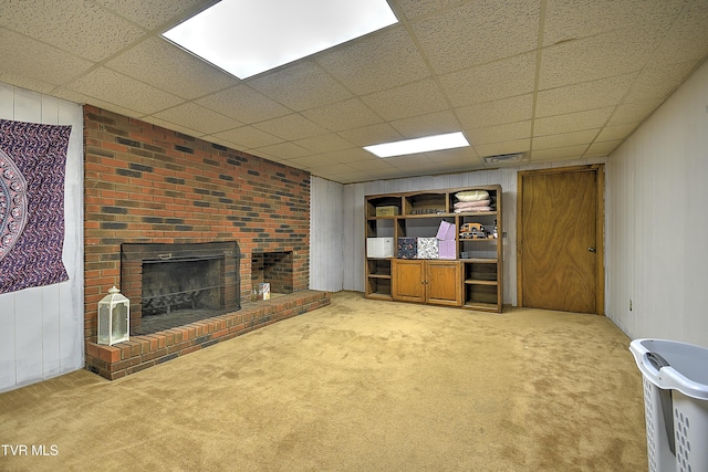 unfurnished living room featuring wood walls, a fireplace, carpet floors, and a drop ceiling