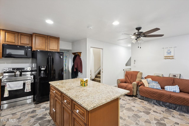 kitchen with light stone countertops, a center island, ceiling fan, and black appliances