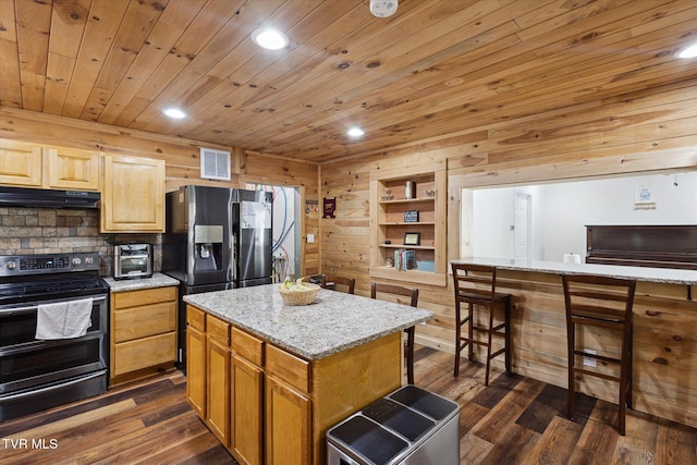 kitchen featuring light stone counters, appliances with stainless steel finishes, dark hardwood / wood-style floors, and a center island