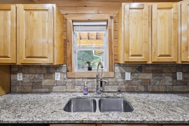 kitchen with light stone countertops, sink, and light brown cabinets