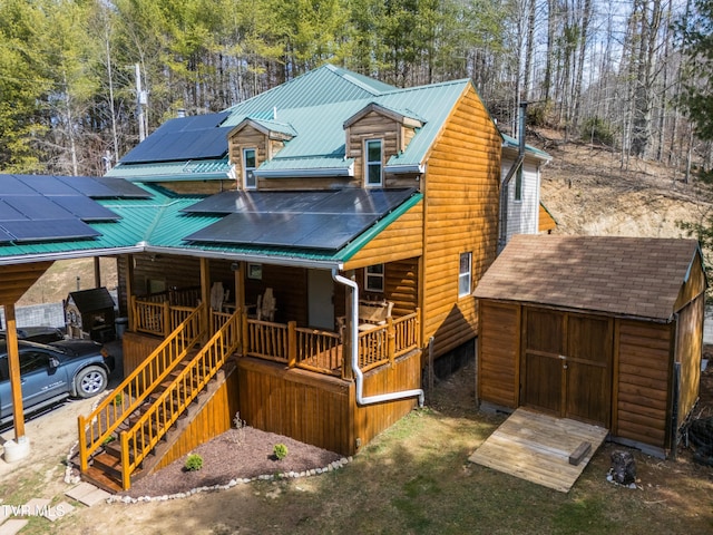 2191 Hubert Taylor Rd, Mountain City, TN 37683 - view of front facade with a porch, roof mounted solar panels, an outdoor structure, a storage unit, and log veneer siding