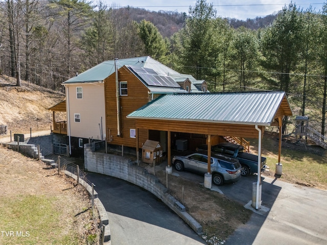 2191 Hubert Taylor Rd, Mountain City, TN 37683 - rustic home with solar panels, a forest view, aphalt driveway, metal roof, and a carport
