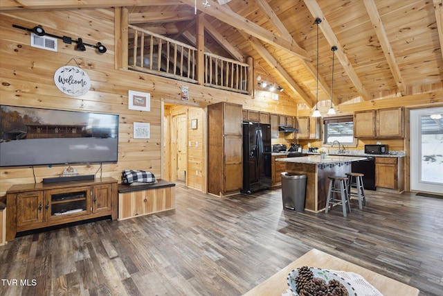 kitchen with a kitchen island, wooden walls, beamed ceiling, and dark hardwood / wood-style floors