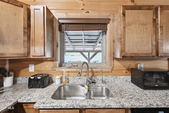 kitchen featuring wood ceiling, dishwasher, wood walls, light stone countertops, and sink