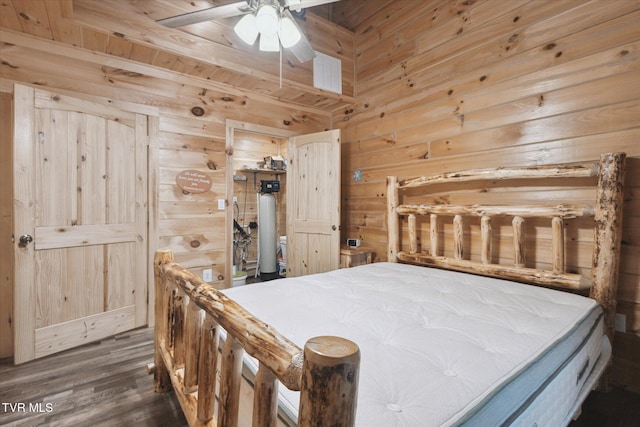 bedroom with ceiling fan, dark wood-type flooring, and wooden walls