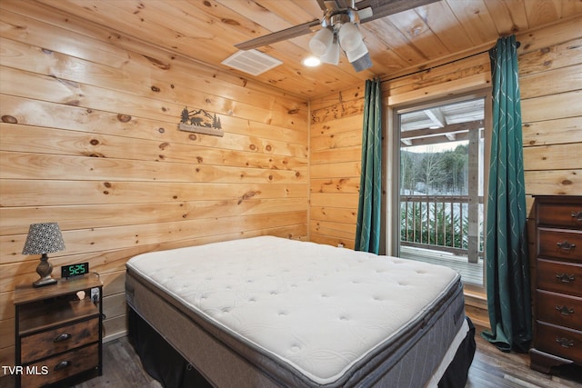 bedroom featuring access to outside, dark wood-type flooring, wood walls, wood ceiling, and ceiling fan