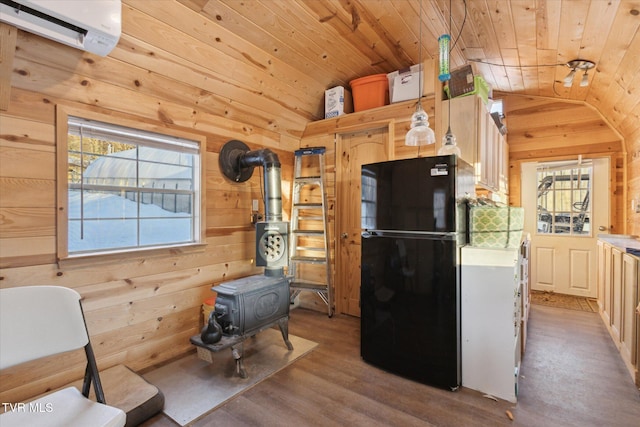 kitchen featuring wooden ceiling, wood walls, a wall mounted AC, black fridge, and a wood stove