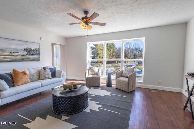 living room with dark wood-type flooring, plenty of natural light, a textured ceiling, and ceiling fan